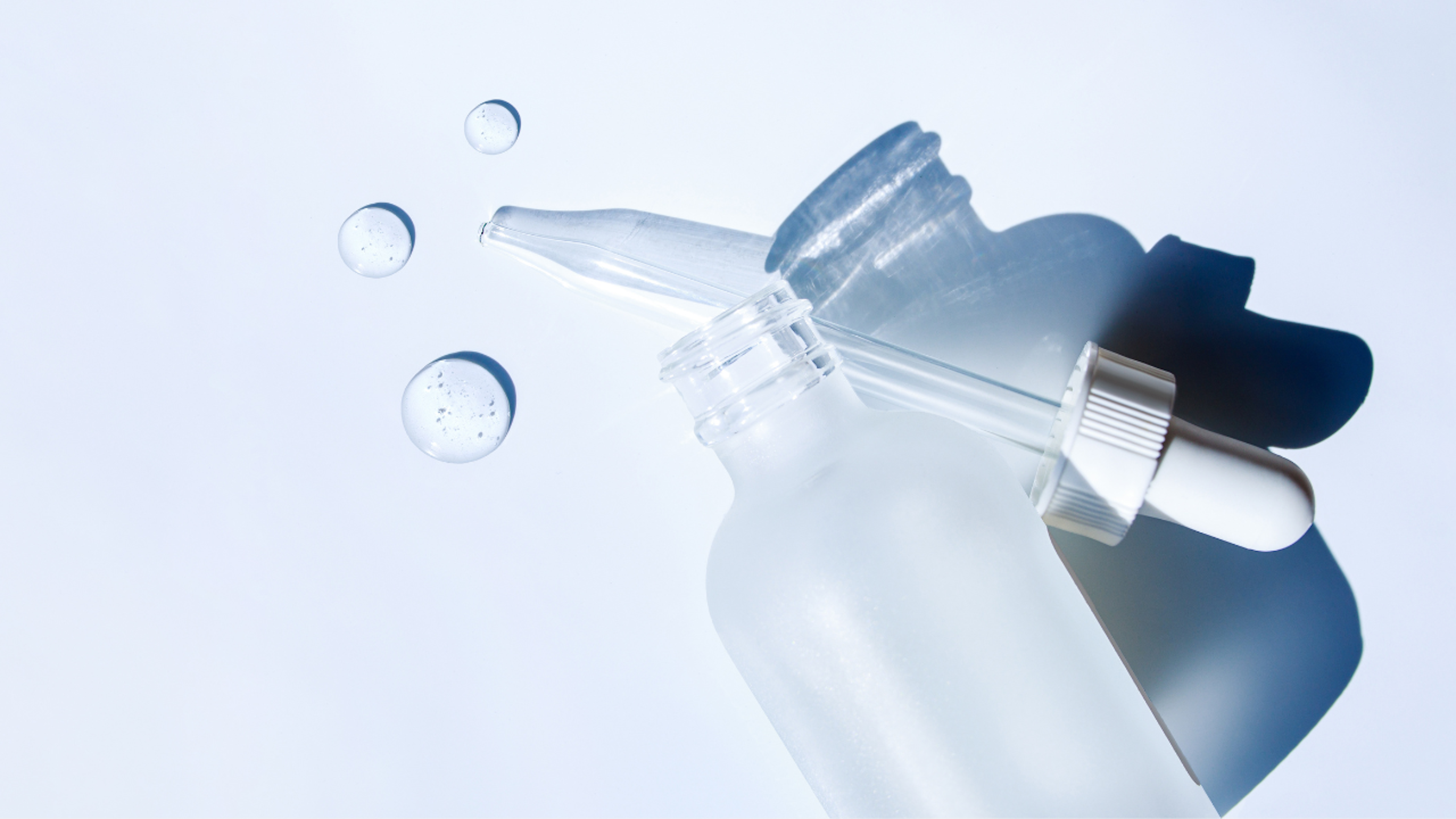 Image of glass serum bottle, dropper and 3 droplets