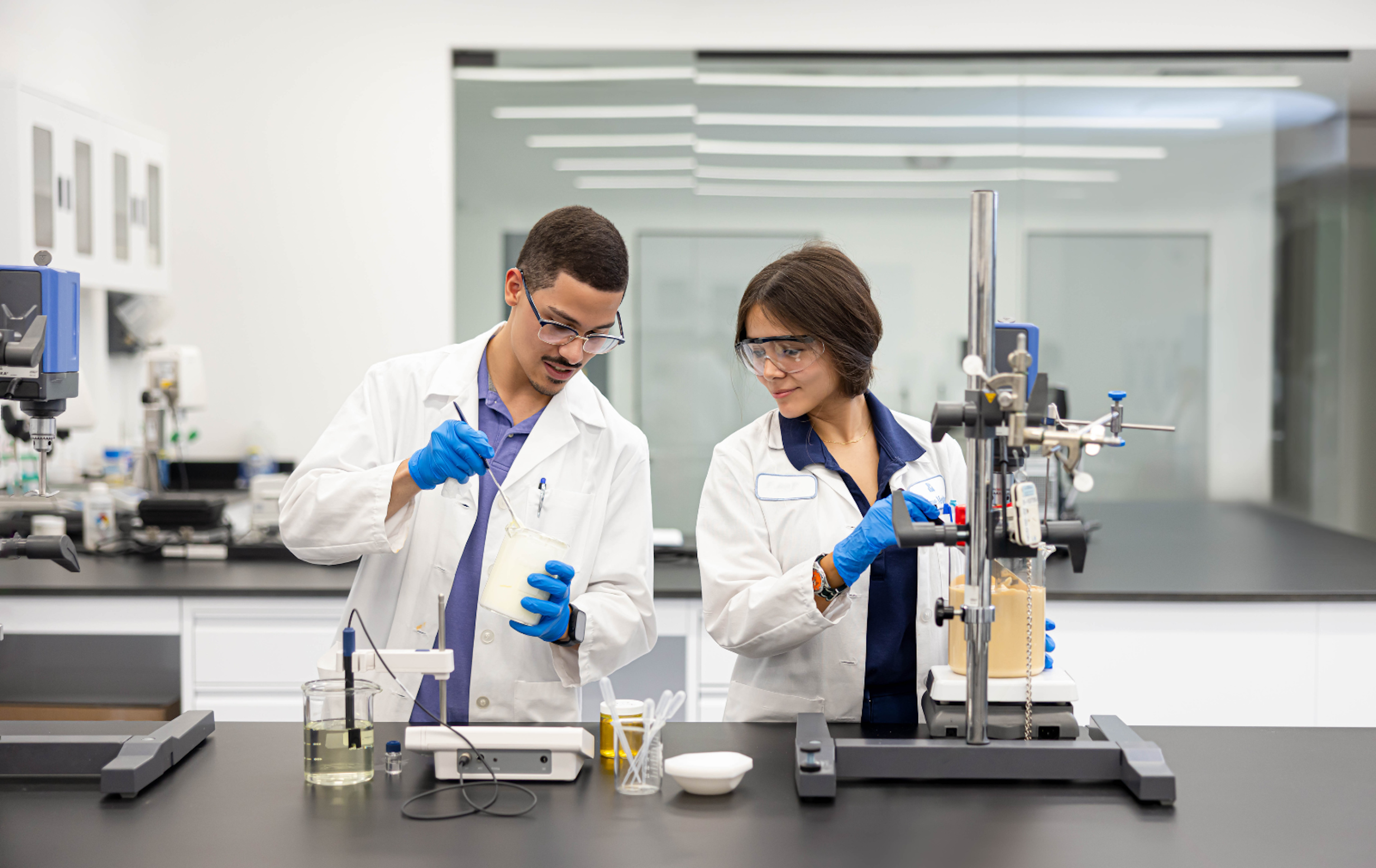 man and woman in lab coats mixing beauty products in lab